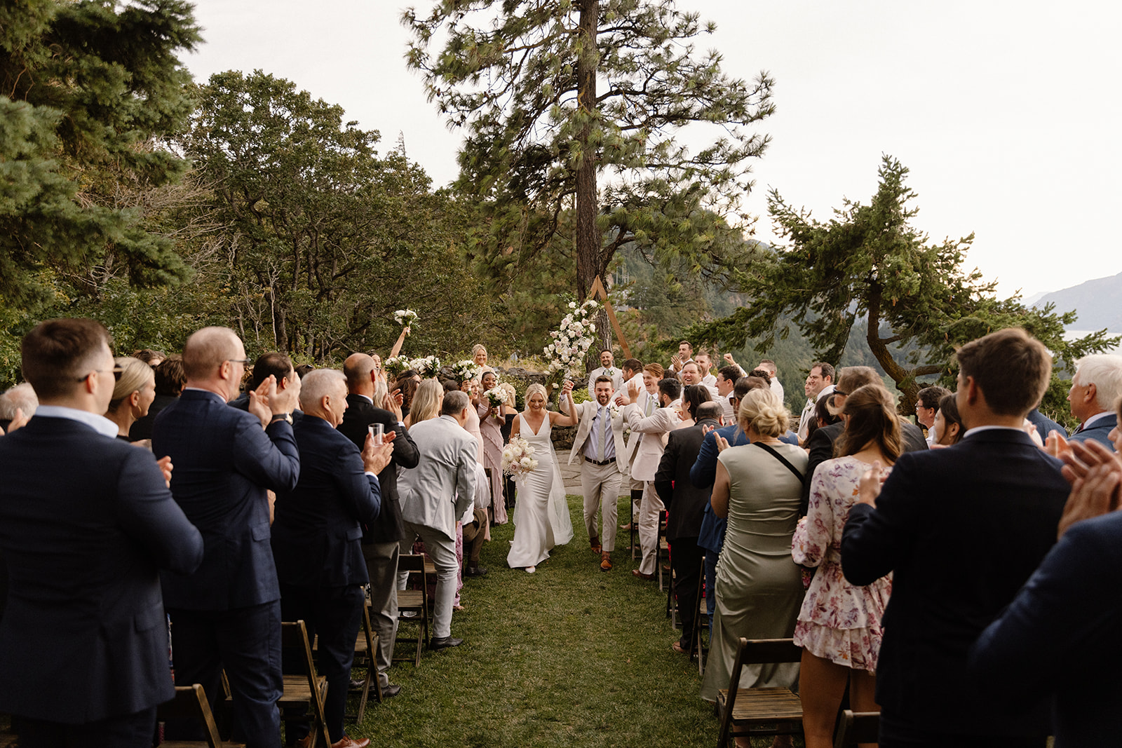 Bride and groom walking down the aisle surrounded by their family and friends