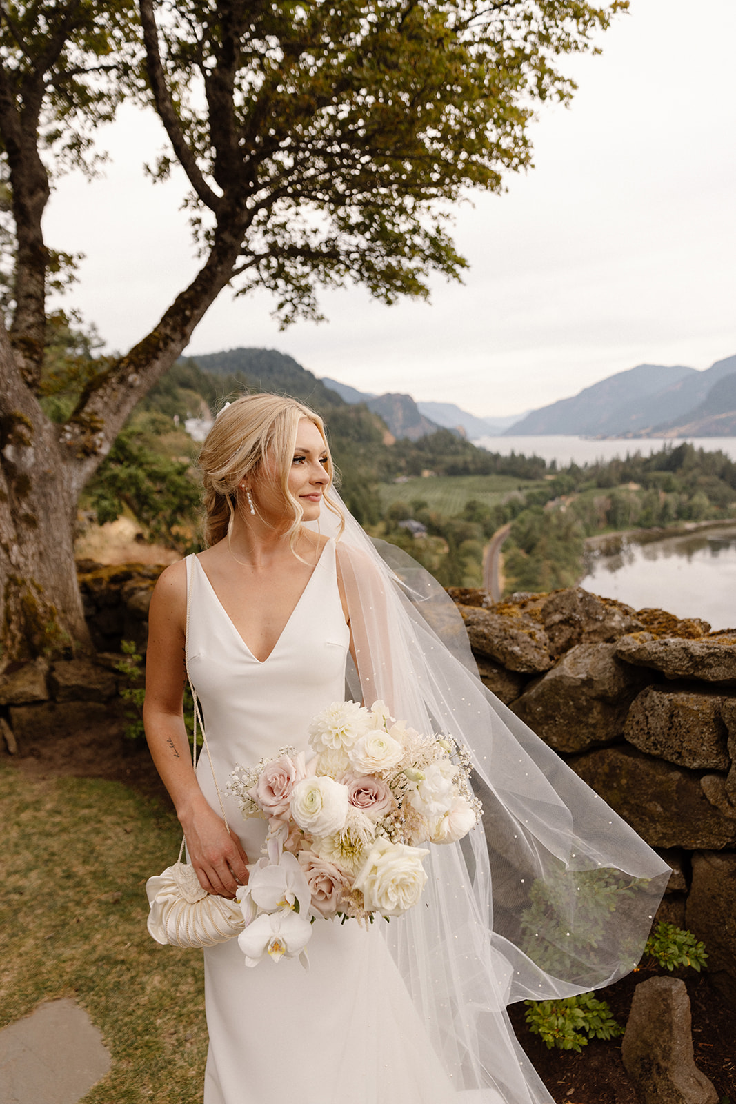Portrait of the bride in a stunning wedding gown, surrounded by lush greenery at The Griffin House, with a soft smile and an elegant veil cascading down her shoulders.