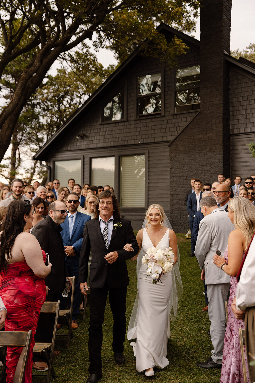 Bride walking down the aisle at The Griffin House, surrounded by blooming flowers
